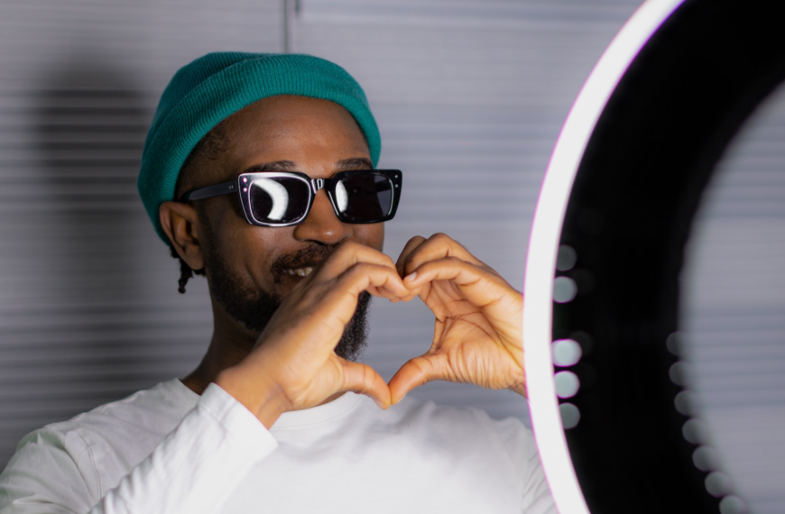Photo of an influencer making a heart symbol with his hands standing behind a ring light