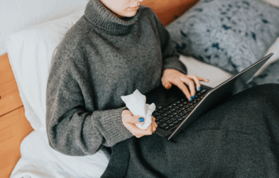 Person holding tissues while using laptop