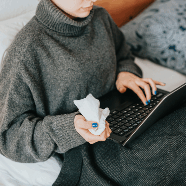 Person holding tissues while using laptop