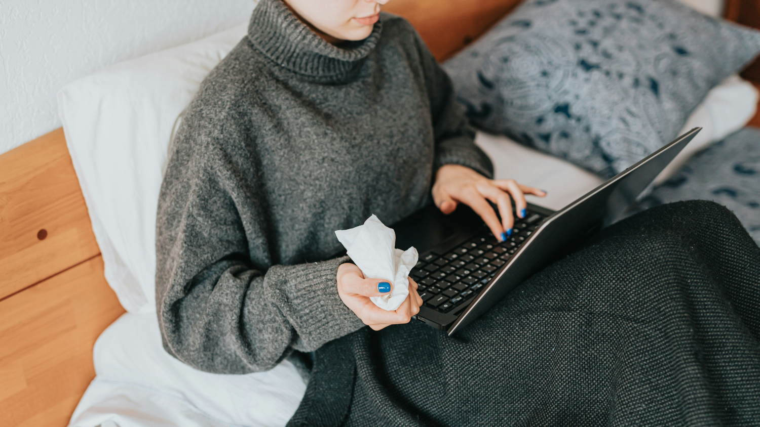 Person holding tissues while using laptop
