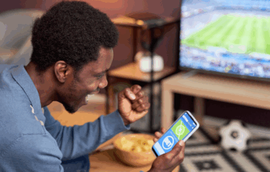 Man cheering at phone showing bet on sport match