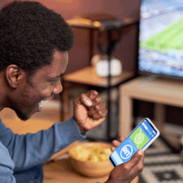 Man cheering at phone showing bet on sport match