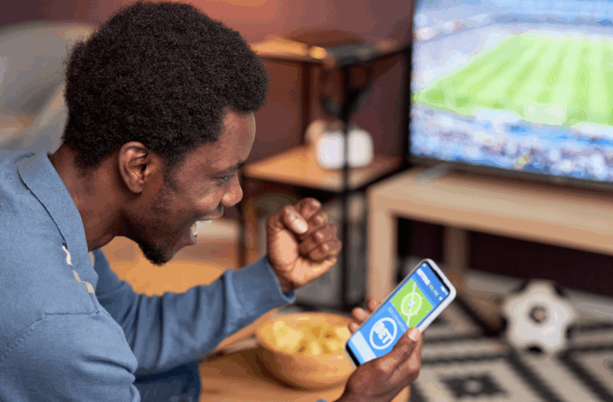 Man cheering at phone showing bet on sport match